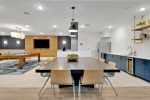 Modern co-working space with kitchen, dining table, and pool table for collaborative work and leisure activities.