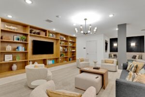 Modern living room with wooden shelves, cozy seating, and contemporary lighting. Neutral tones create a relaxing atmosphere.