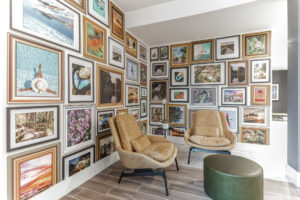 Gallery wall with diverse framed artwork and cozy seating area in stylish, modern room.
