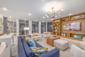 Modern living room with blue and beige seating, wall art, bookshelf, and stylish chandelier. Cozy and elegant design.