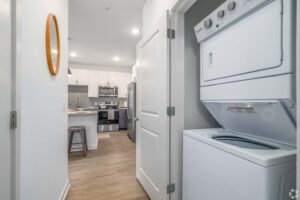 Compact laundry appliances in modern kitchen layout with white cabinetry and stainless steel appliances.
