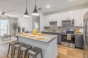 Modern kitchen with stainless steel appliances, granite countertops, and dining area with bar stools.
